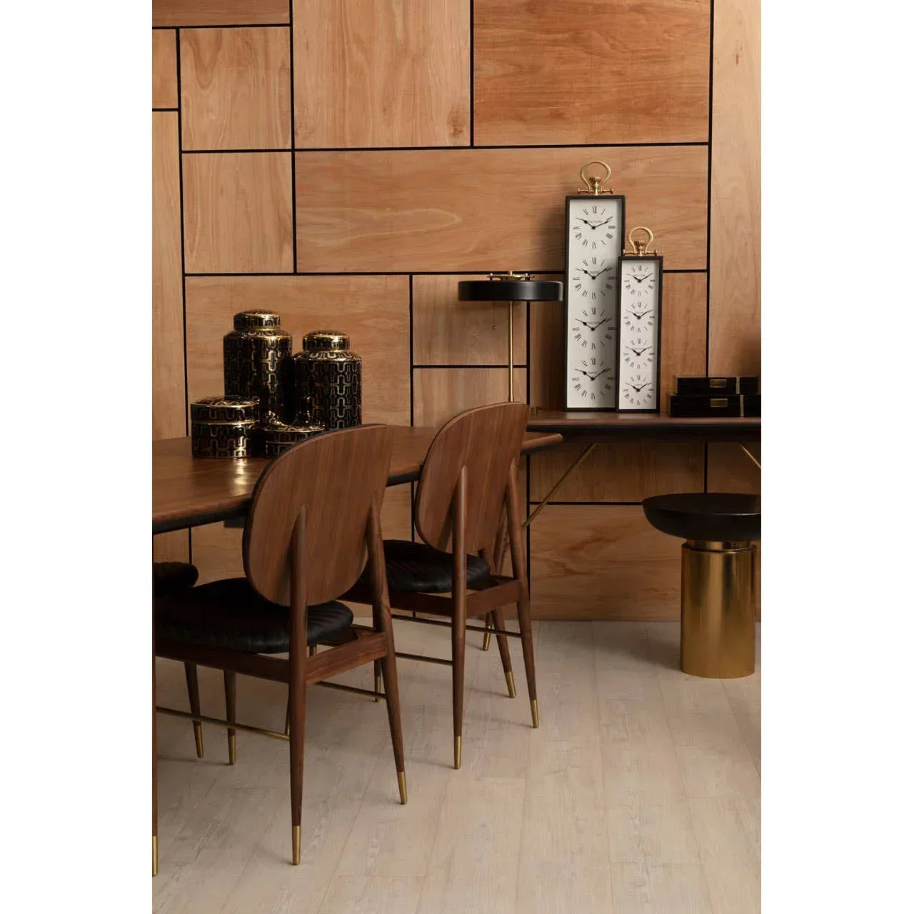 Walnut dining table and chairs with gold accents in a modern wood-paneled dining room