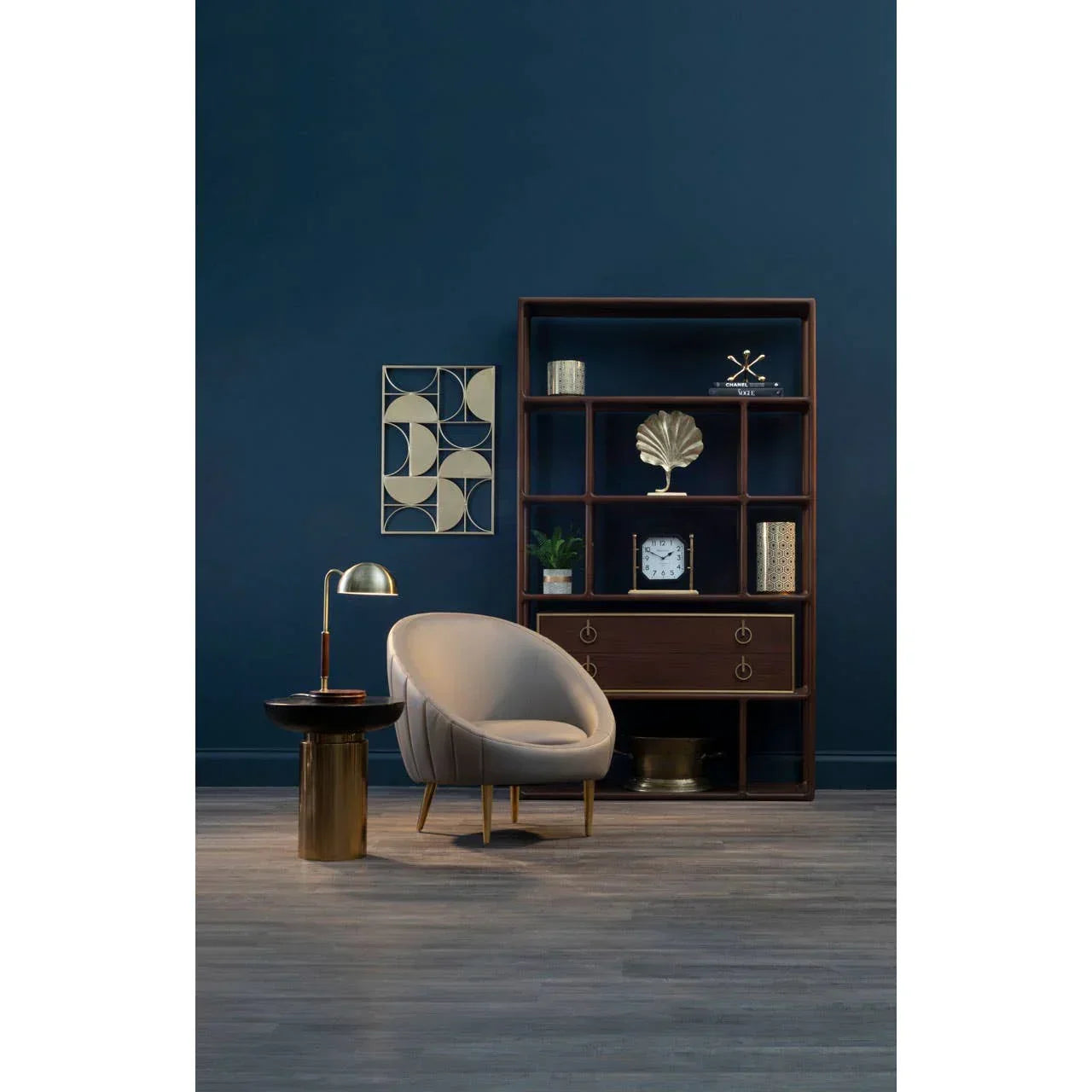 Modern accent chair and round side table beside wooden shelving unit with decor in living room