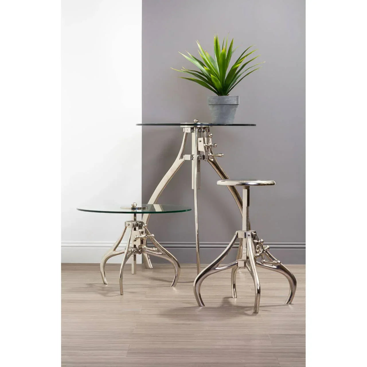 Chrome and glass bistro table set with matching stool and plant in modern room