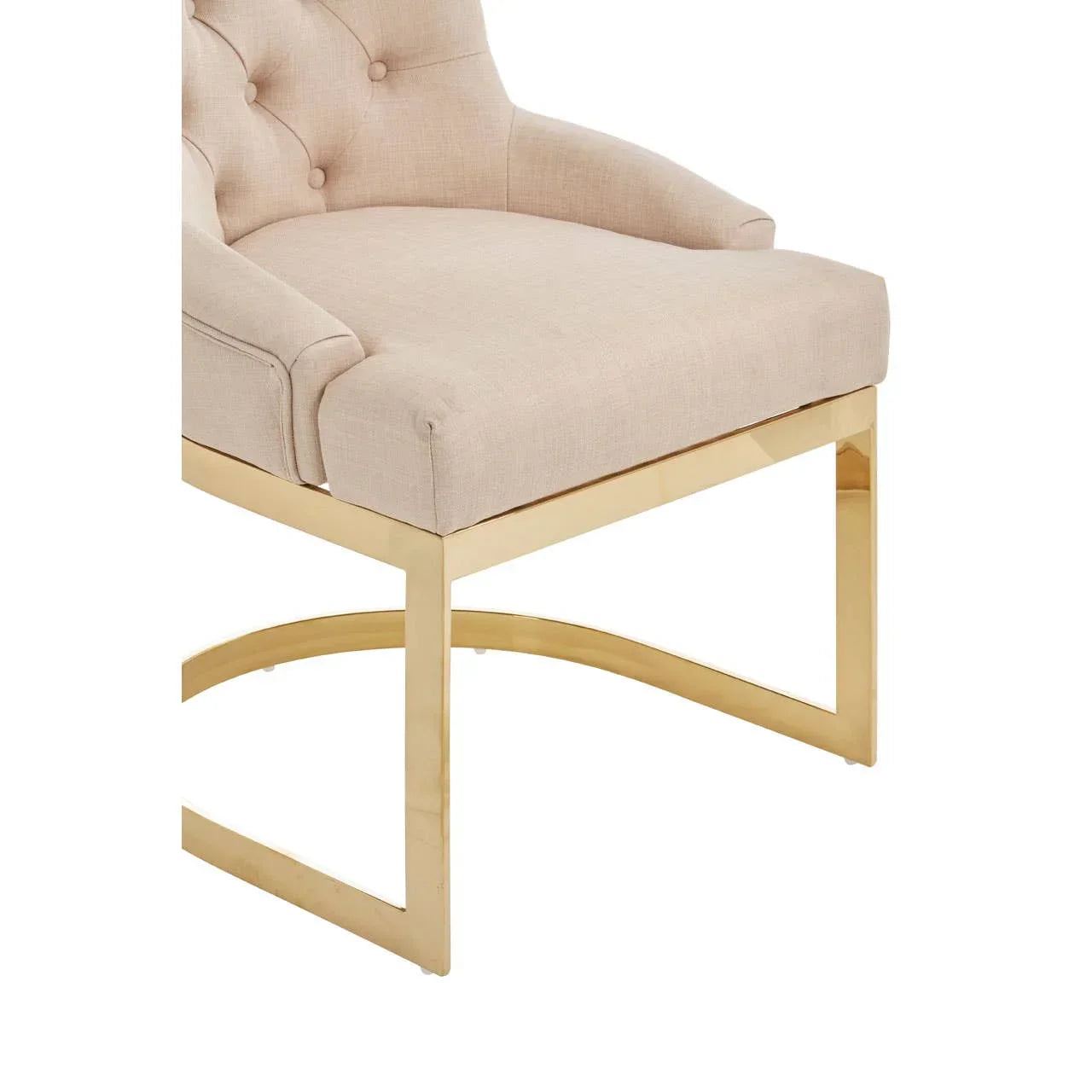 Beige upholstered dining chair with tufted back and gold metal legs, side angle view