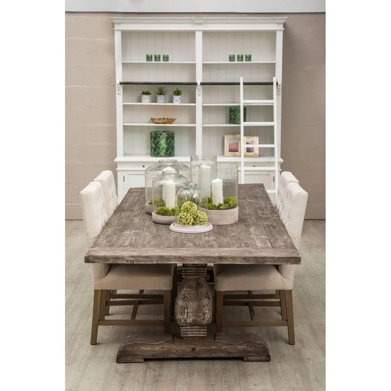 Rustic wooden dining table with beige chairs and glass candle centerpieces in dining room