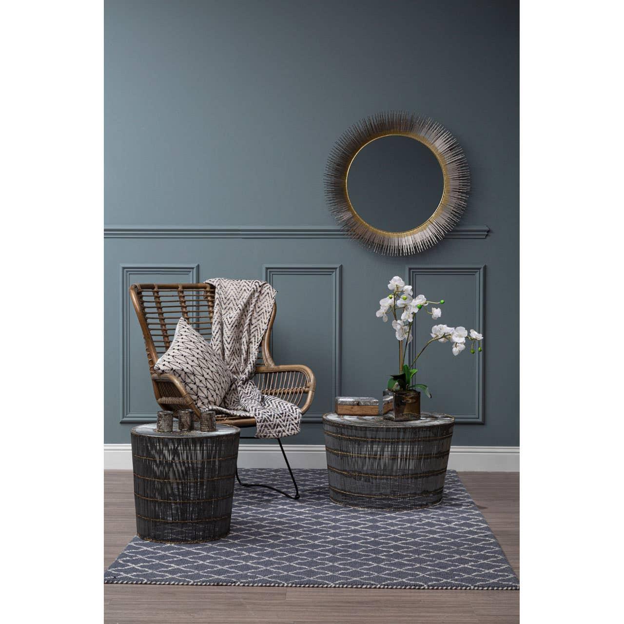 Rattan accent chair with geometric throw, two wire side tables and decorative round mirror