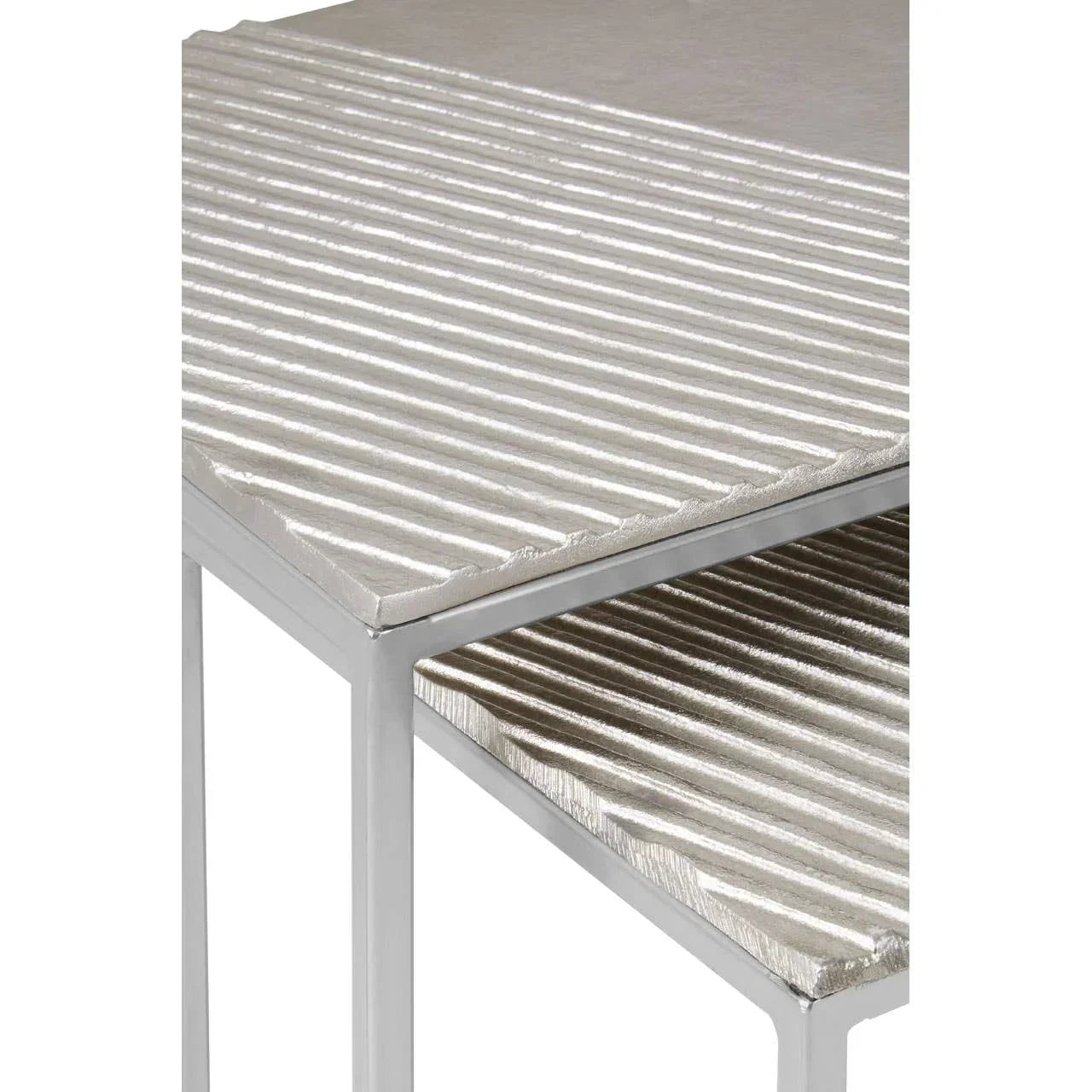 Silver metal nesting tables with ridged tops and modern frame, close-up view