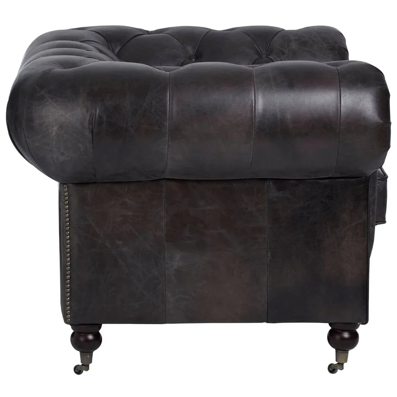 Close-up of dark brown leather Chesterfield sofa arm with deep button tufting and castor legs