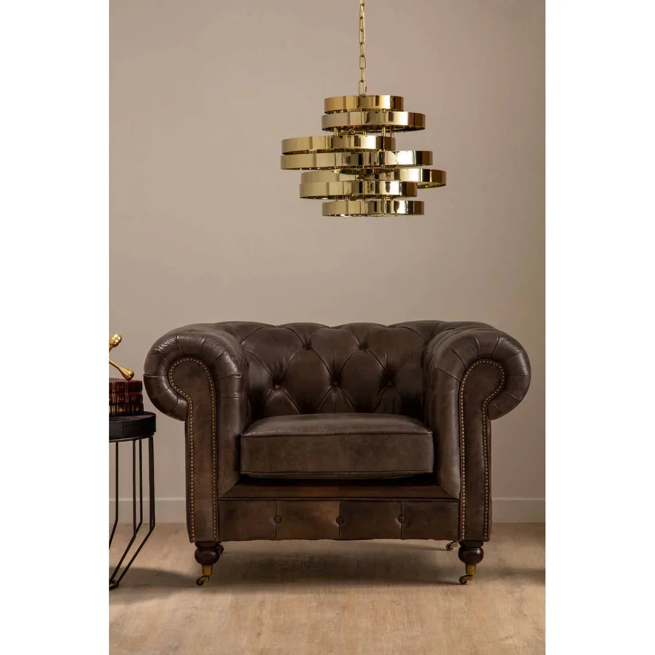 Dark brown leather armchair with button tufting under gold modern pendant light