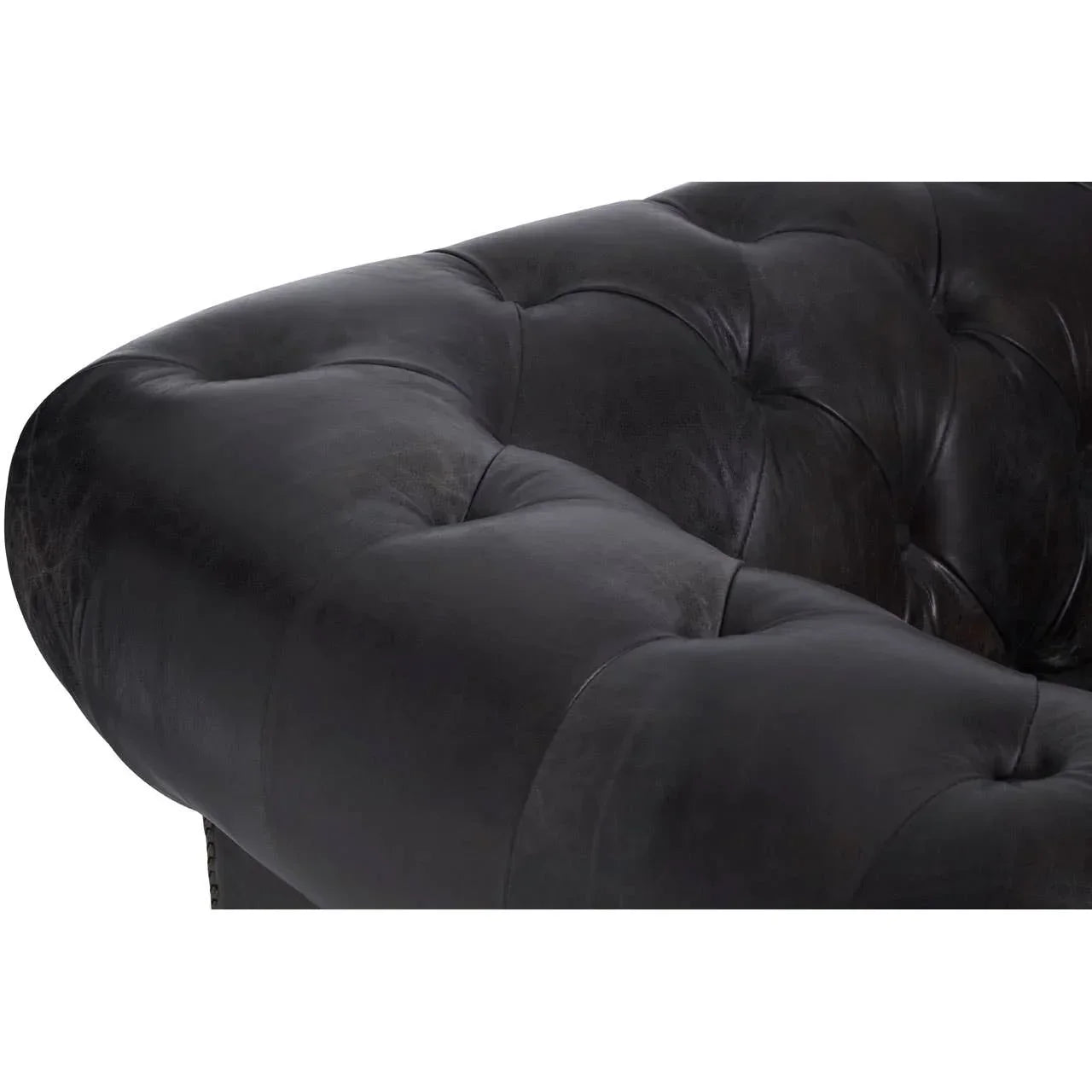 Close detail of black leather sofa arm with deep button tufting