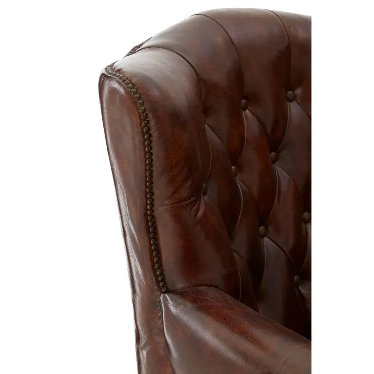 Close up of brown leather armchair with button tufting and decorative stud trim