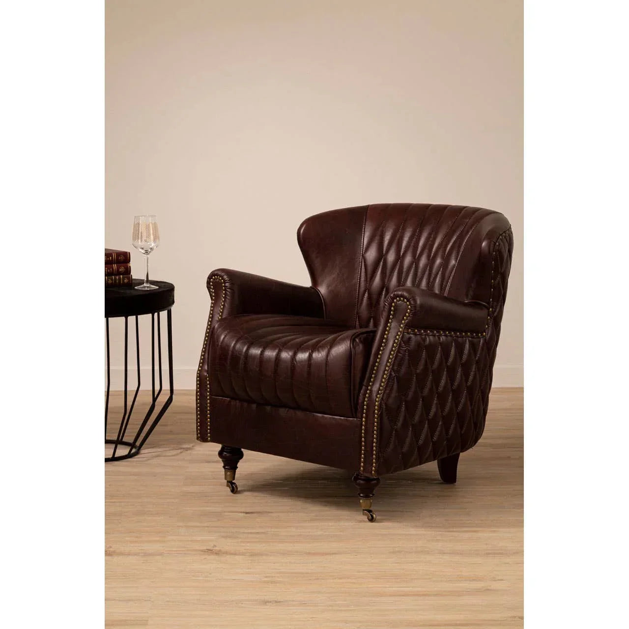 Brown leather armchair with diamond stitching and brass stud detail on wooden floor