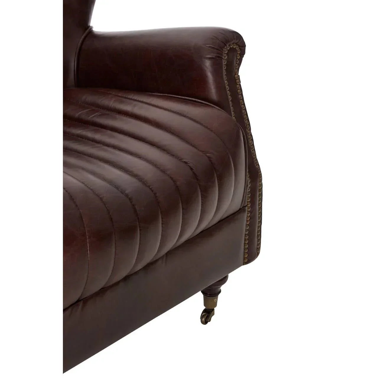 Closeup of brown leather sofa arm and seat with stitched detail and brass nailhead trim