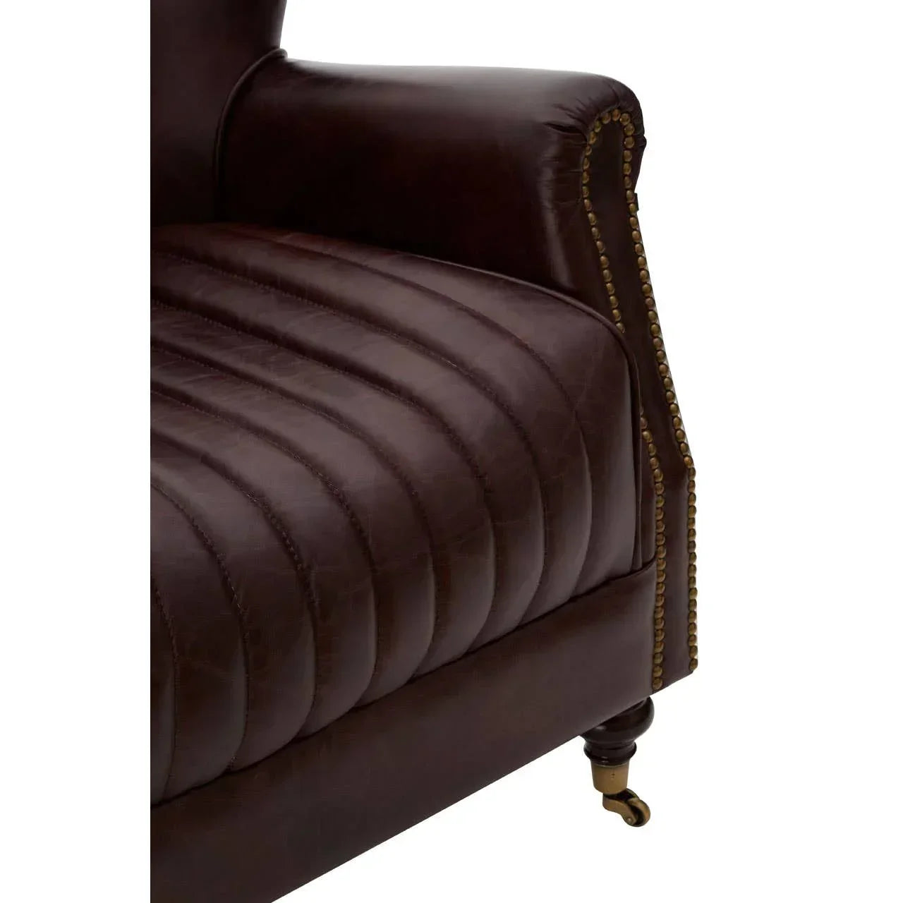 Brown leather sofa arm detail with vertical stitching and brass nailhead trim