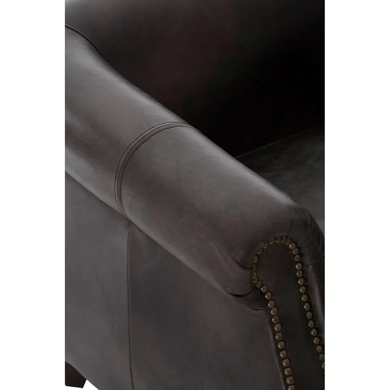 Close-up of brown leather sofa arm with brass nailhead trim