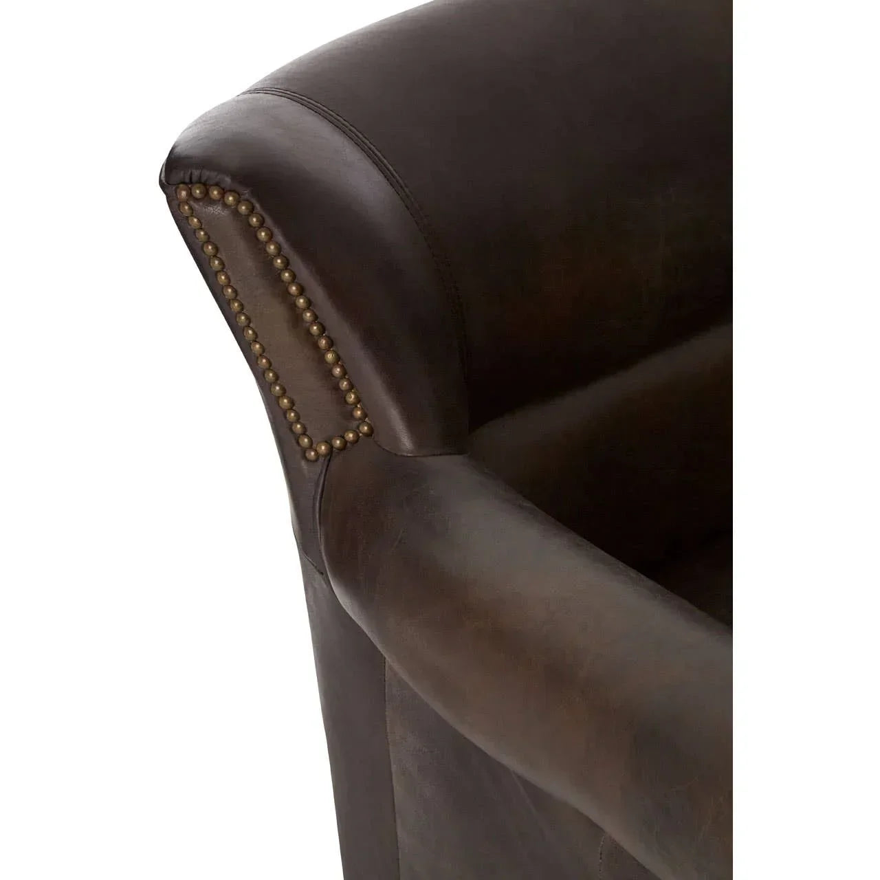 Close-up of brown leather armchair with brass stud detail on armrest