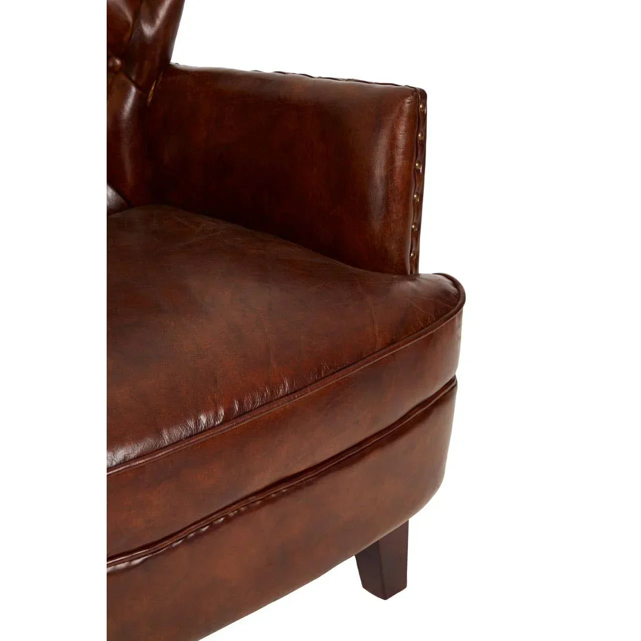 Brown leather armchair close-up with button tufting and studded trim on armrest