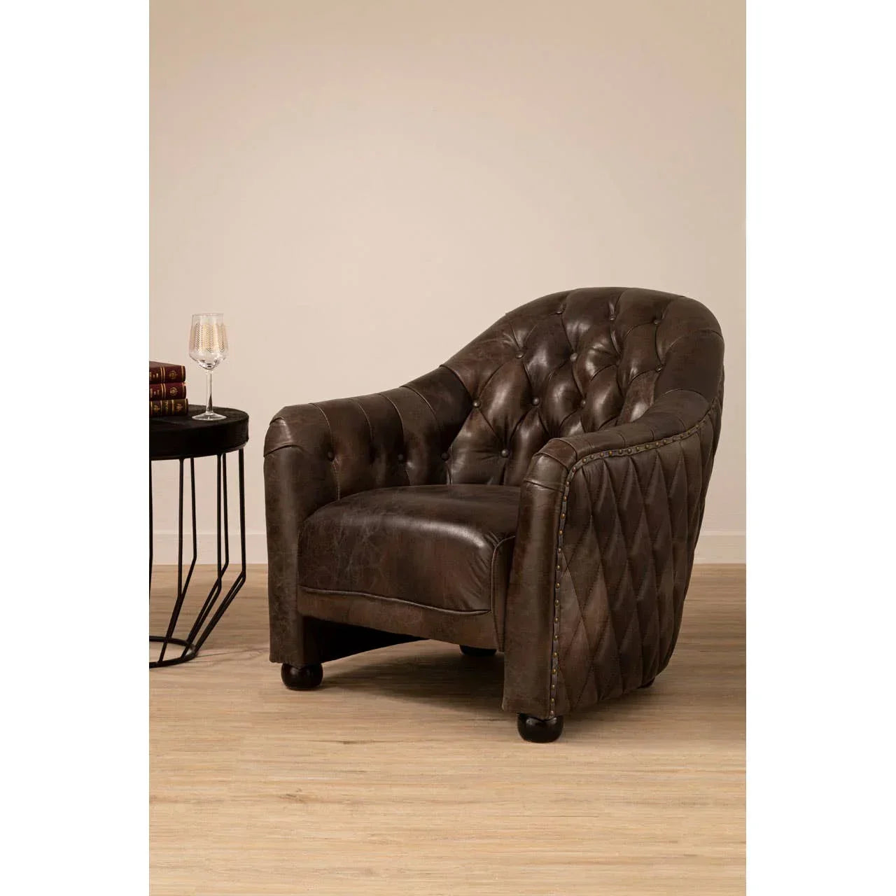 Vintage brown leather armchair with tufted backrest and diamond-stitched sides on wood floor