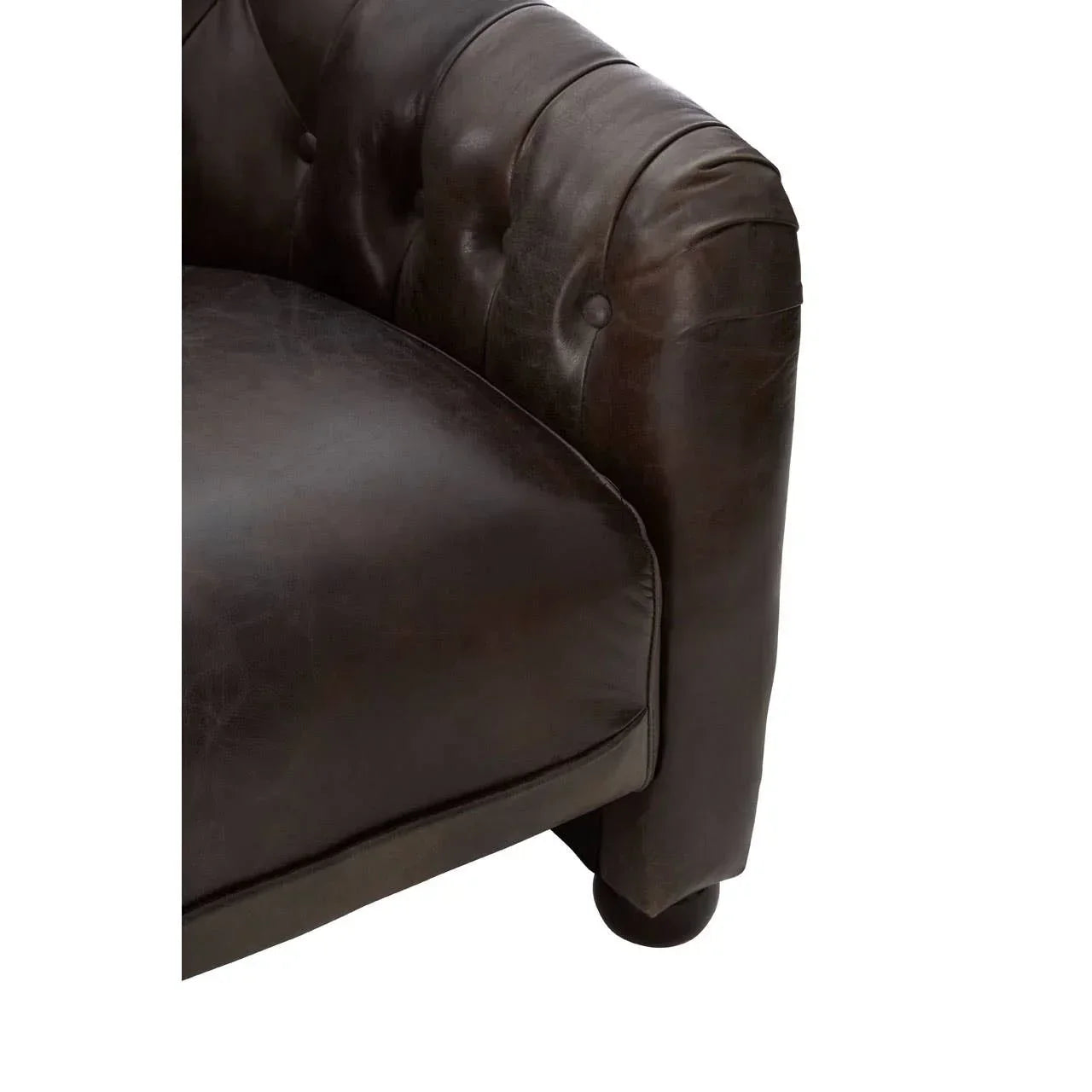 Close-up of brown leather sofa arm with button-tufted detail and cushioned seat