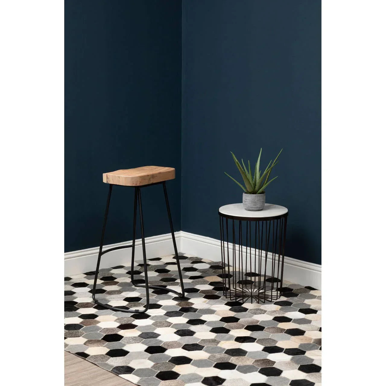 Hexagon pattern rug with modern side table and plant against dark blue wall