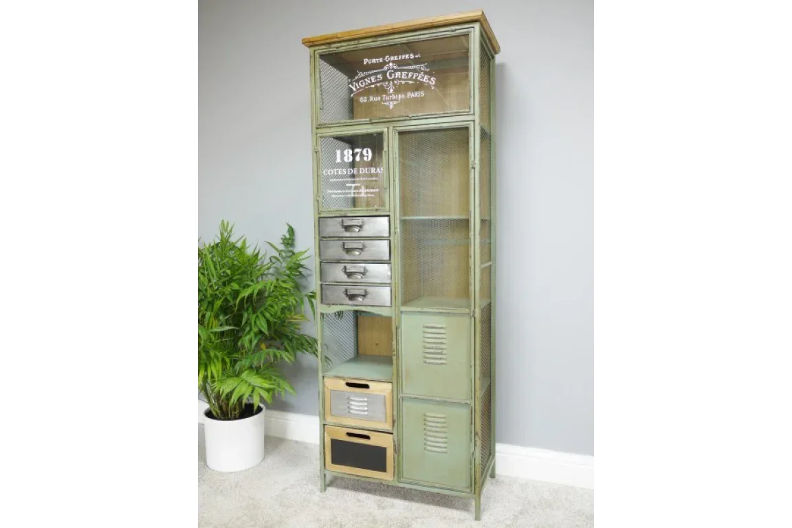 Industrial metal storage cabinet with drawers and mesh doors beside a green potted plant