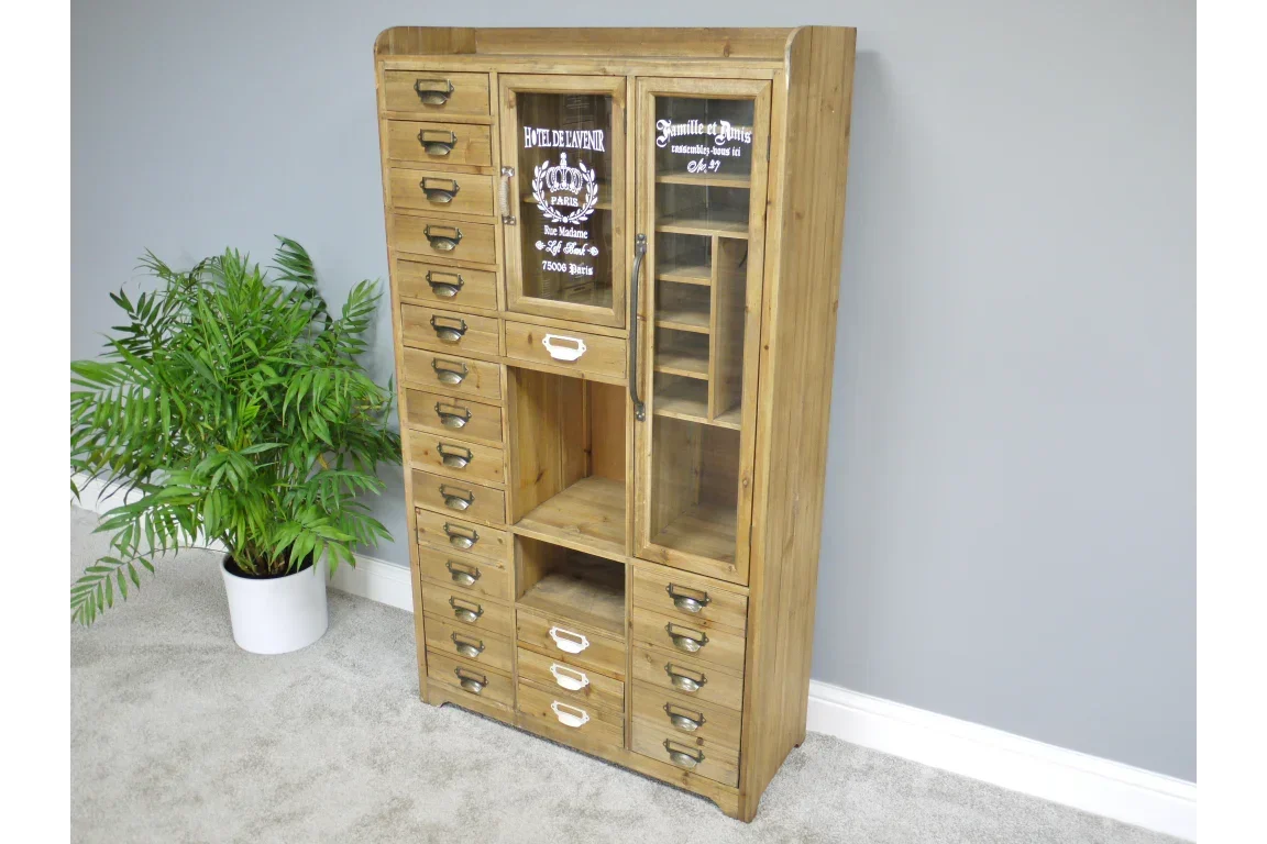 Tall wooden display cabinet with drawers and glass doors beside green potted plant