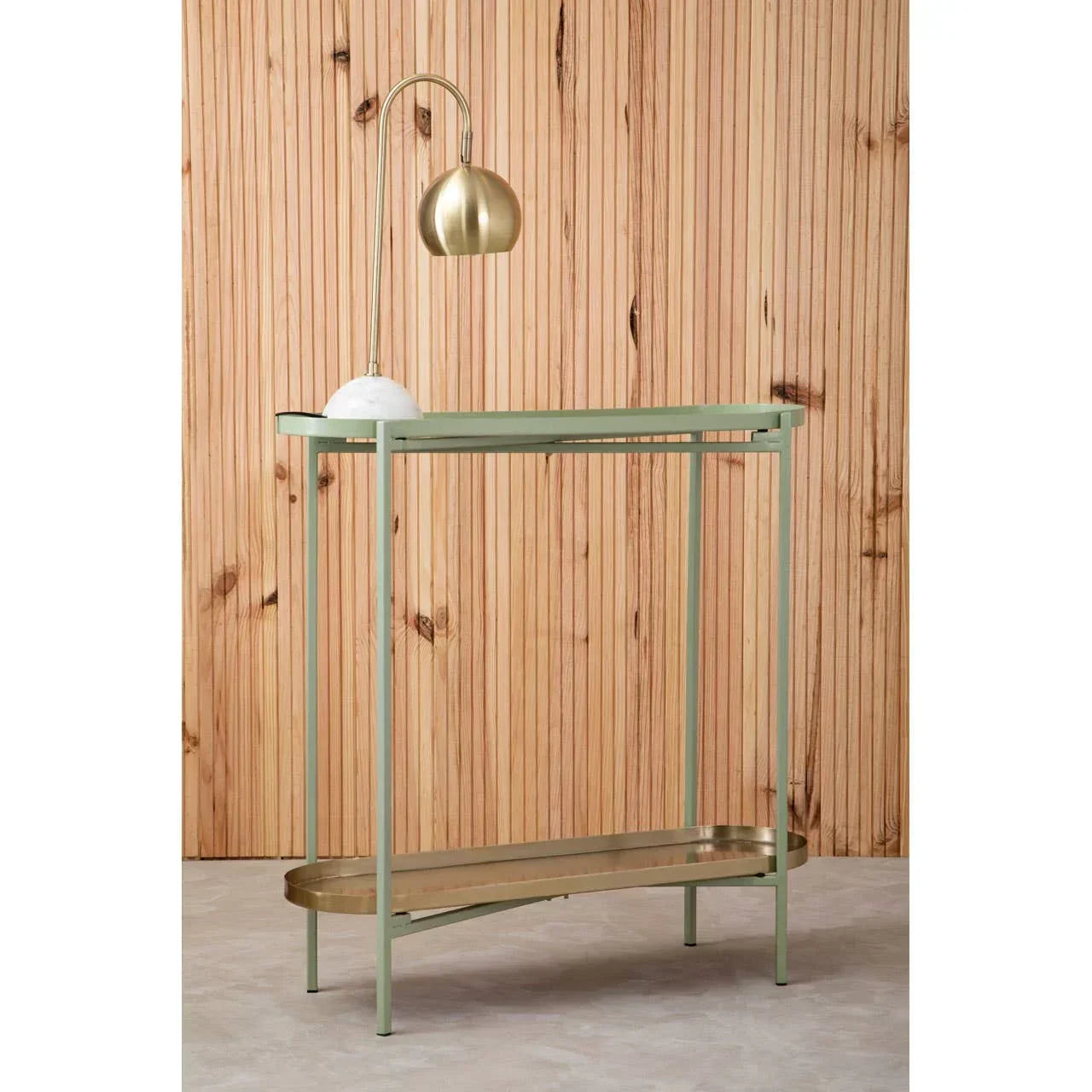 Slim console table with gold frame, lower shelf and brass desk lamp, wood panel backdrop