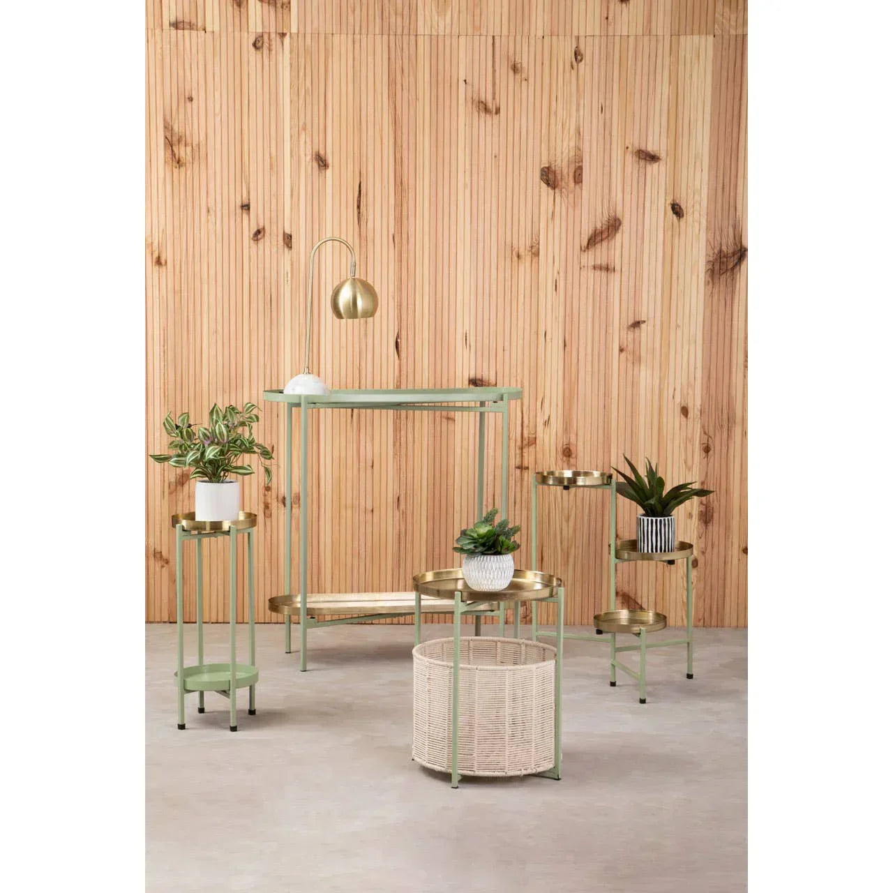 Modern gold and green side tables with metal trays and potted plants against wood panel wall