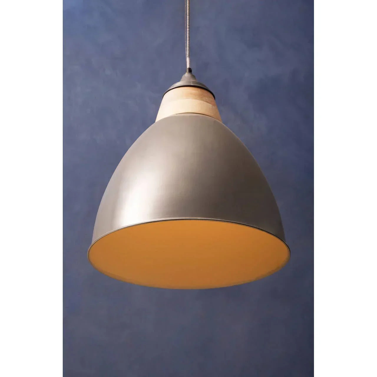 Grey metal pendant light with wooden accent hanging against blue wall