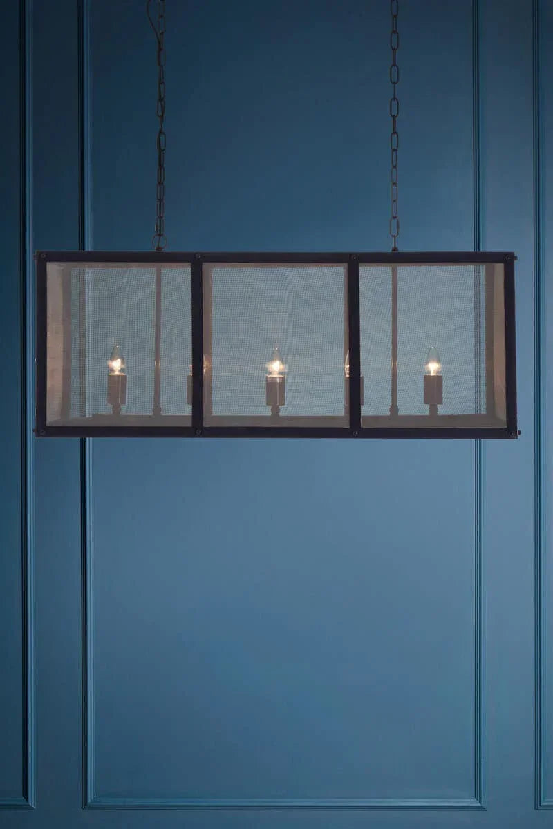 Rectangular industrial pendant light with mesh shade and exposed bulbs against blue wall