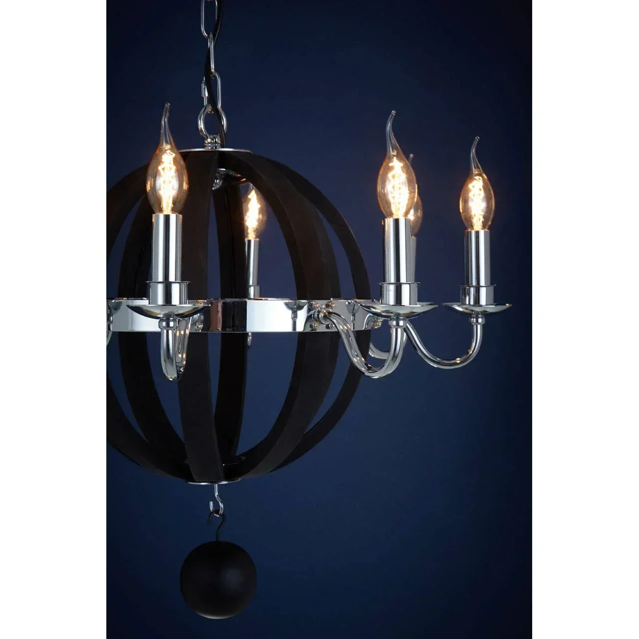 Chrome and black metal chandelier with four candle bulbs against dark blue background