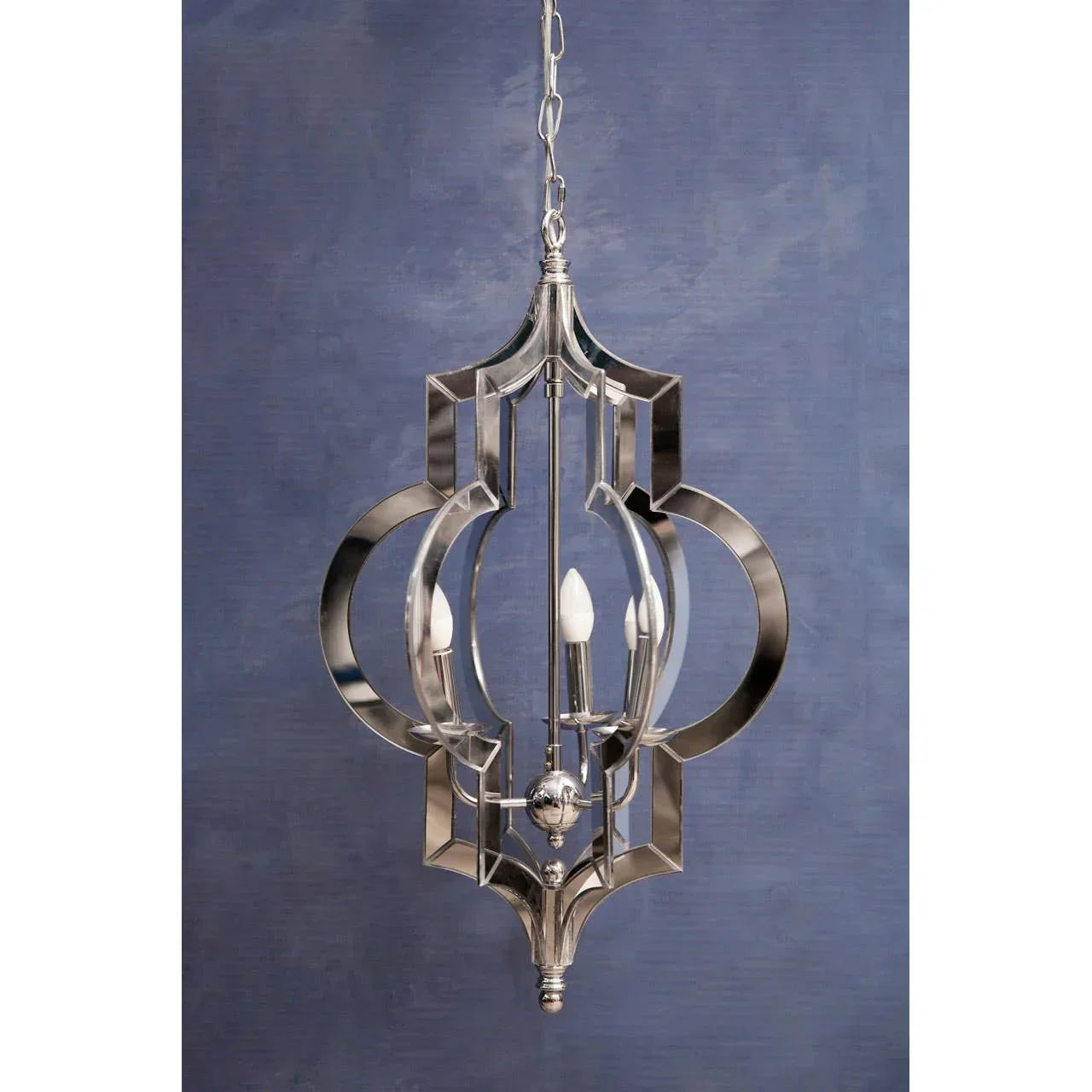 Chrome metal pendant light with candle bulbs and geometric frame against blue wall