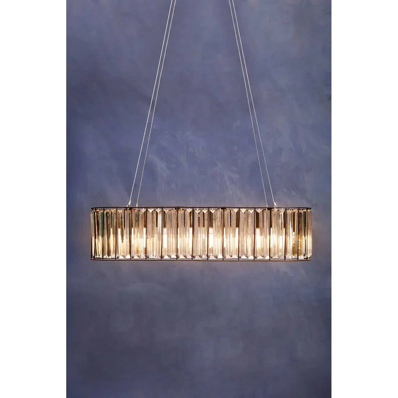 Rectangular crystal pendant light with gold frame and warm bulbs against a blue wall