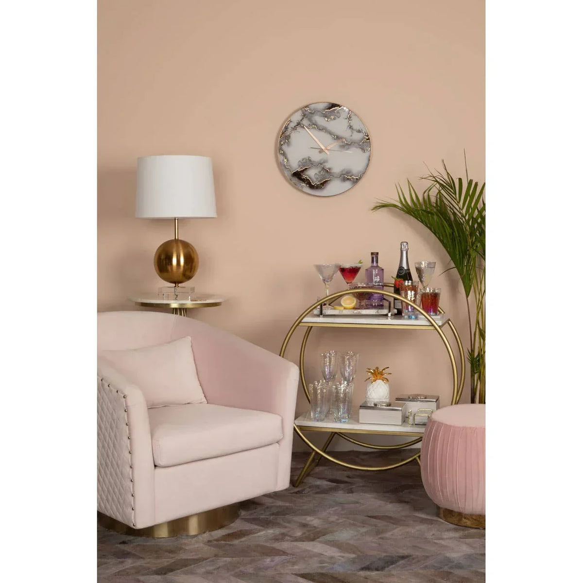 Modern living room with blush velvet armchair, gold bar cart, and marble wall clock decor
