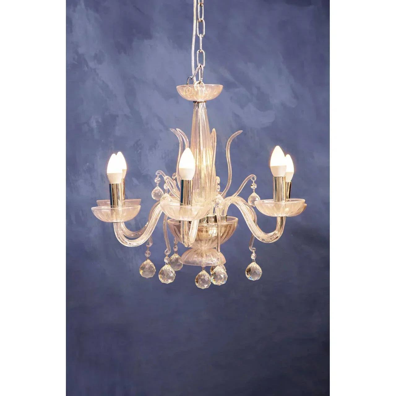 Glass chandelier with crystal drops and candle-style bulbs against blue wall
