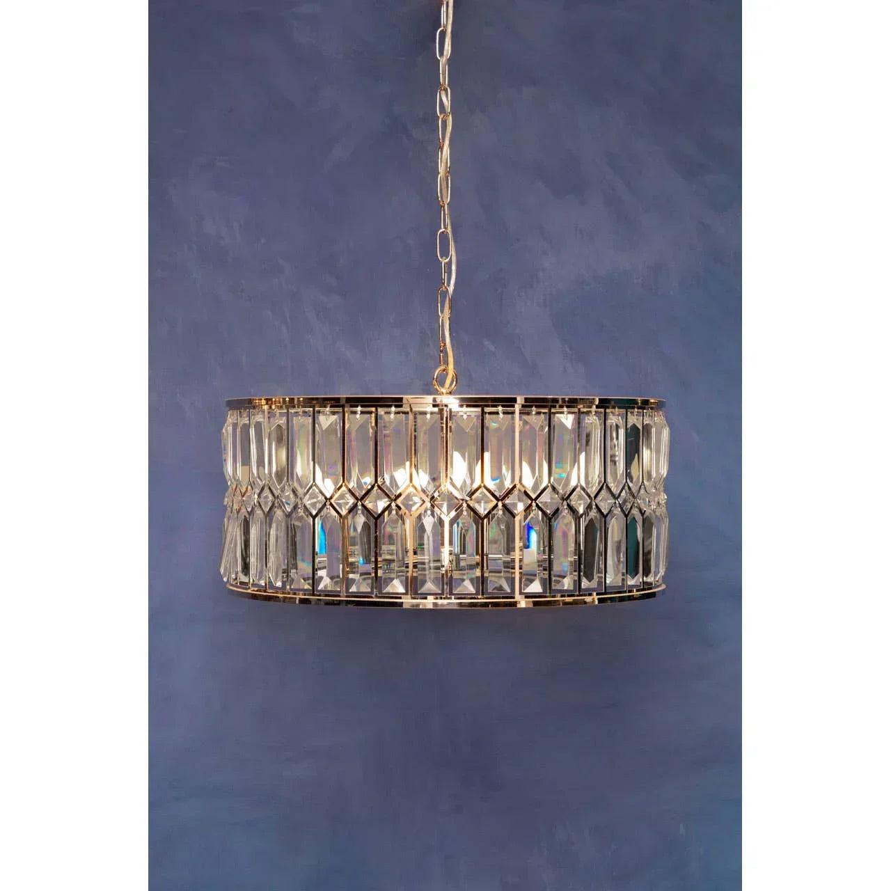 Crystal chandelier pendant light with gold frame against blue wall