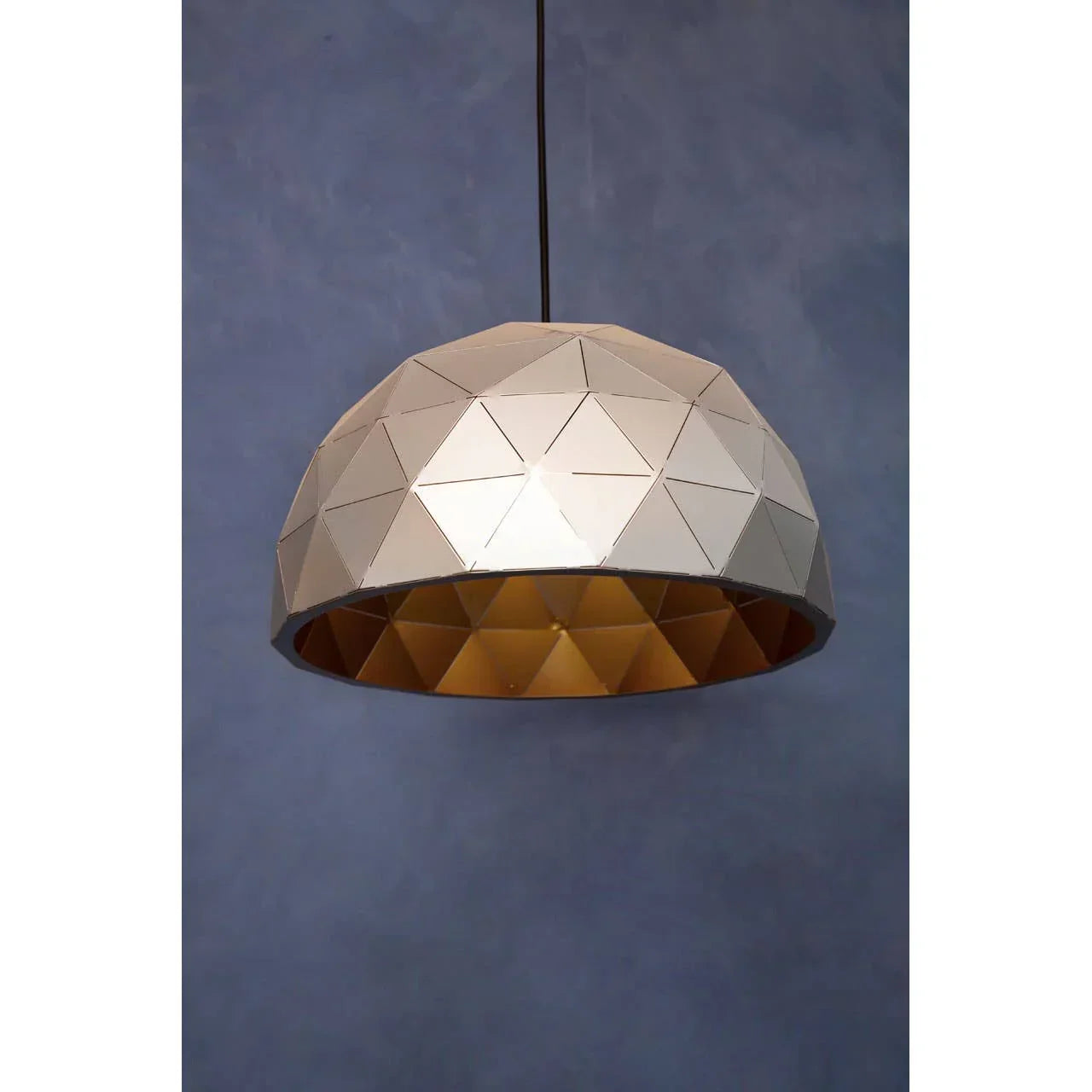 Geometric dome pendant light with gold interior against blue wall