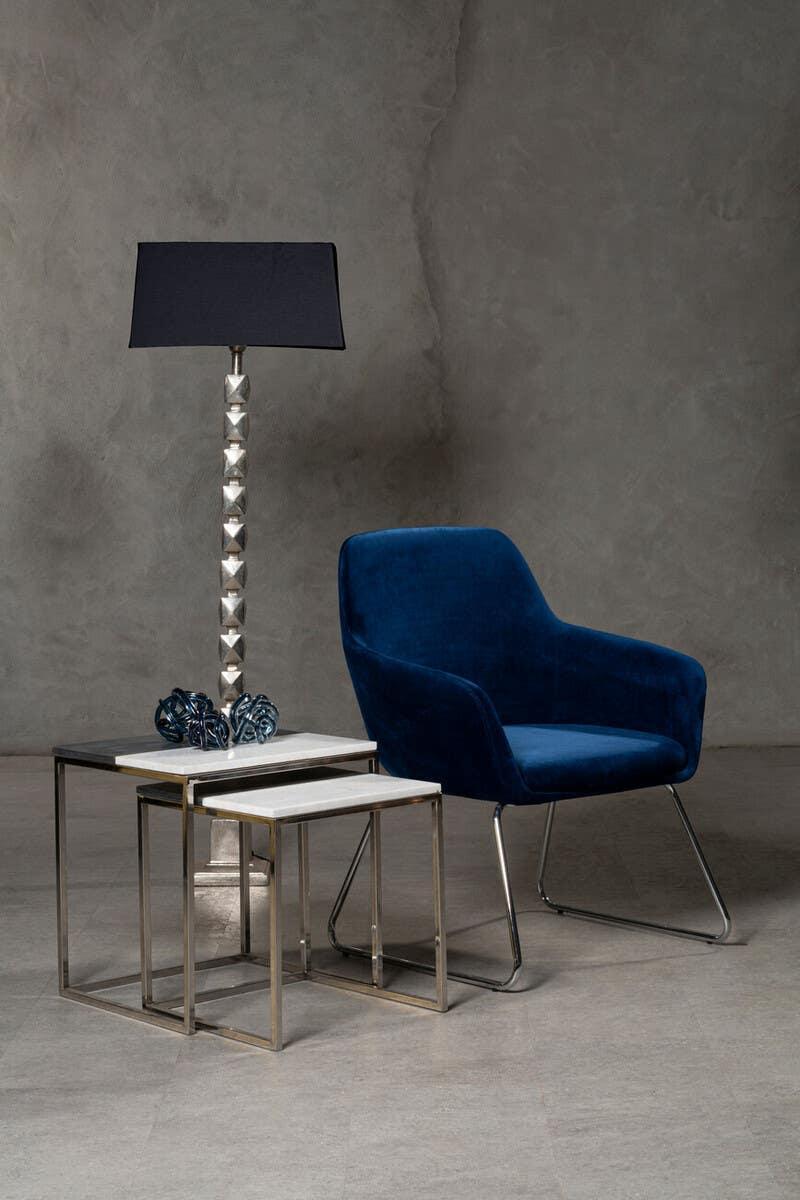 Velvet blue accent chair with modern nesting tables and metallic table lamp