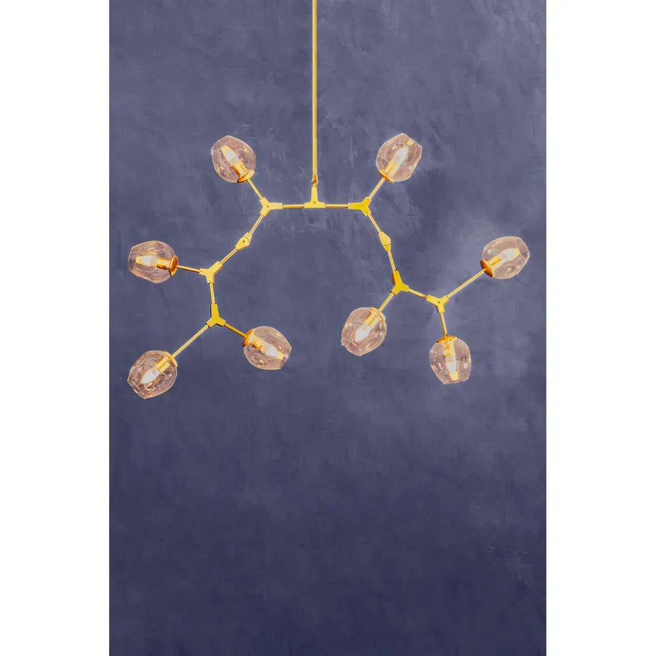 Modern gold ceiling light fixture with eight glass globes against a blue wall