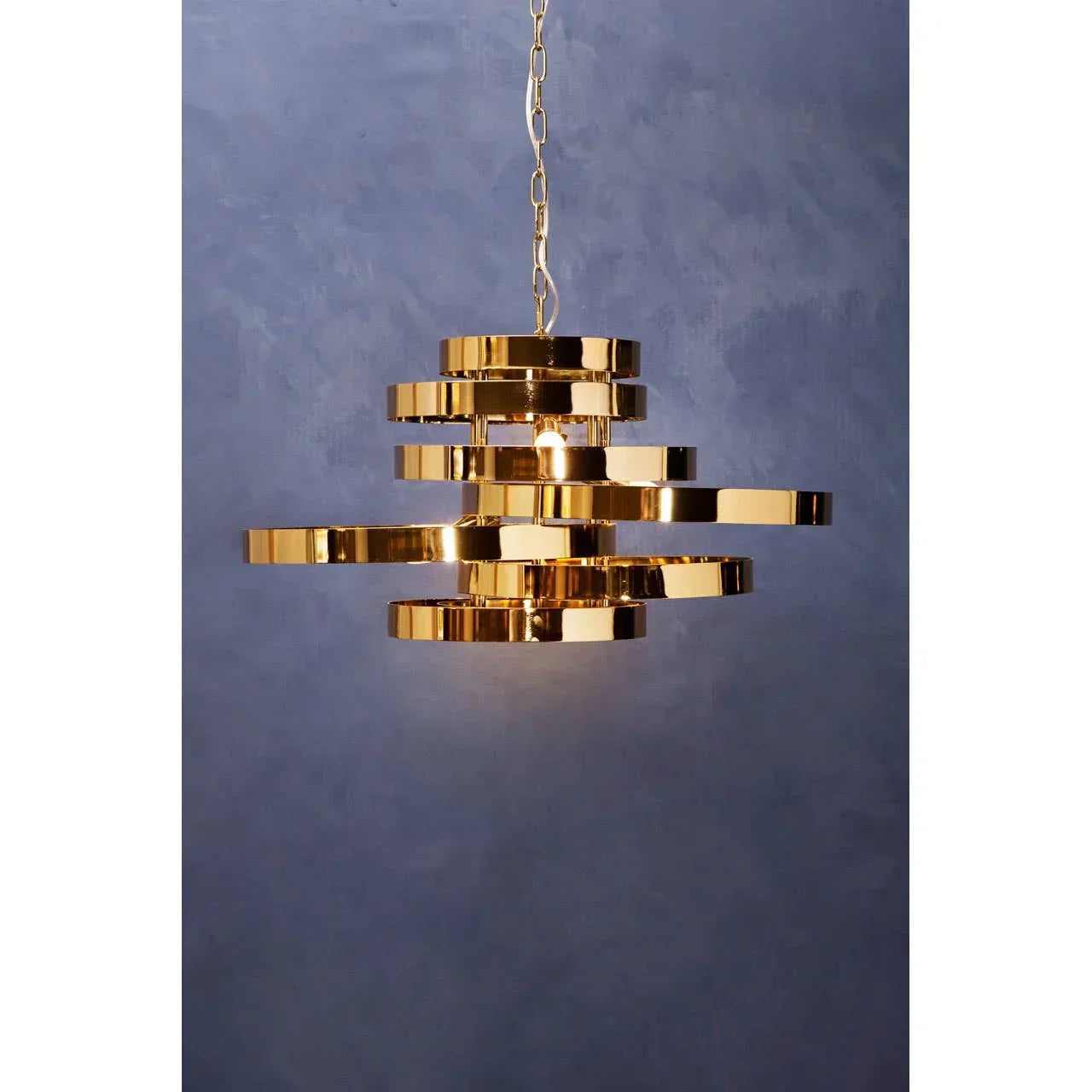 Gold modern pendant light with layered metal rings and chain, hanging against blue wall