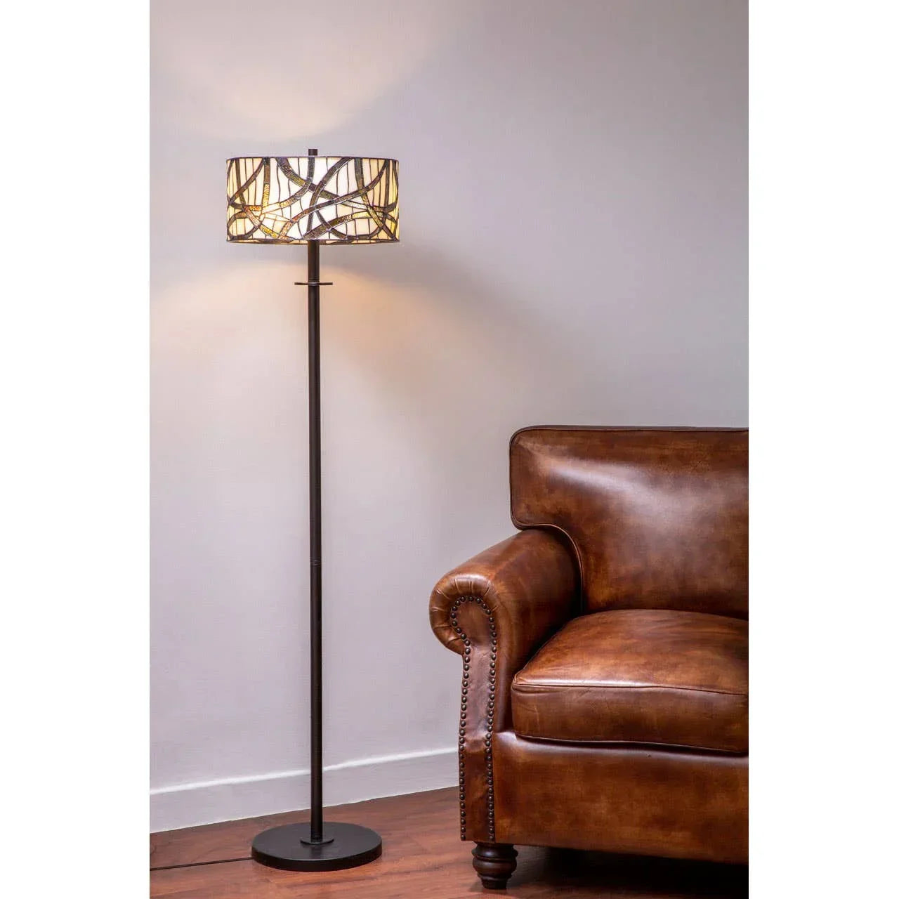 Brown leather sofa next to metal floor lamp with patterned shade in living room