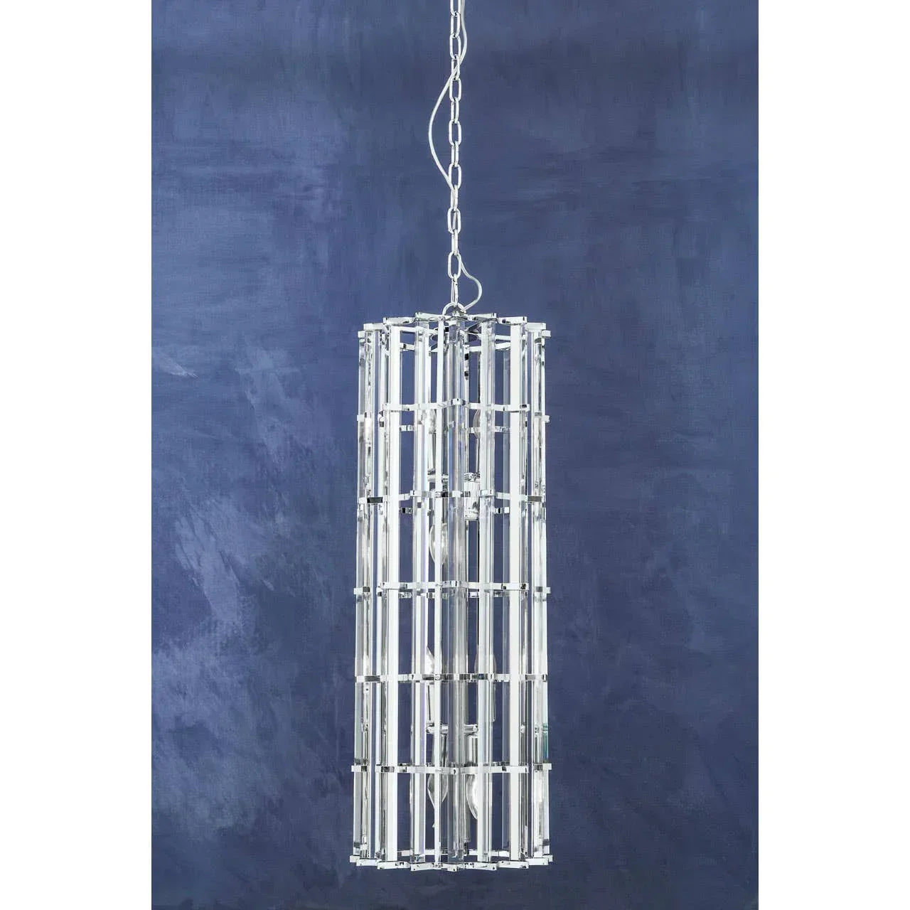 Modern chrome and glass pendant light with cylindrical design against blue wall
