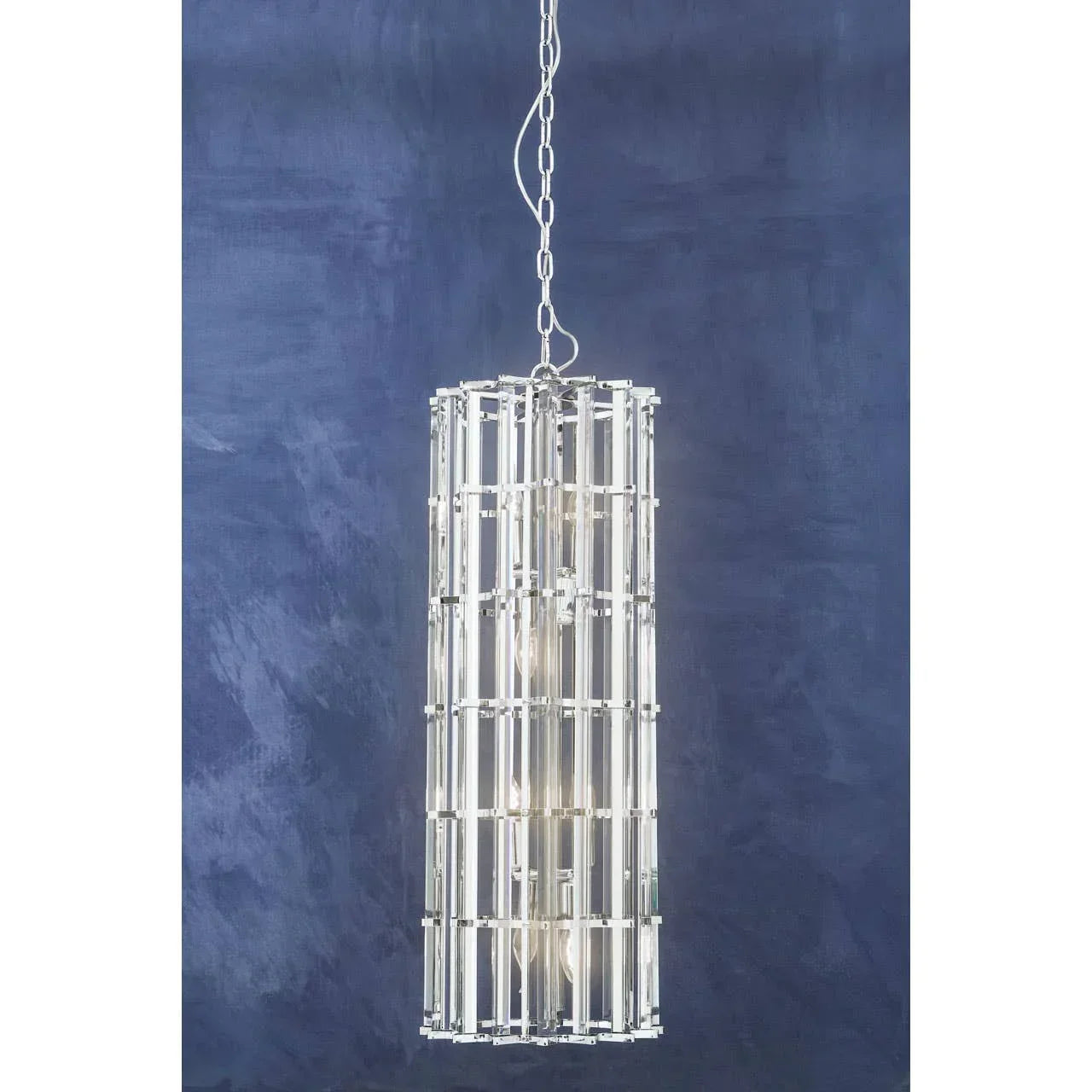 Modern crystal pendant light with cylindrical metal frame against blue wall