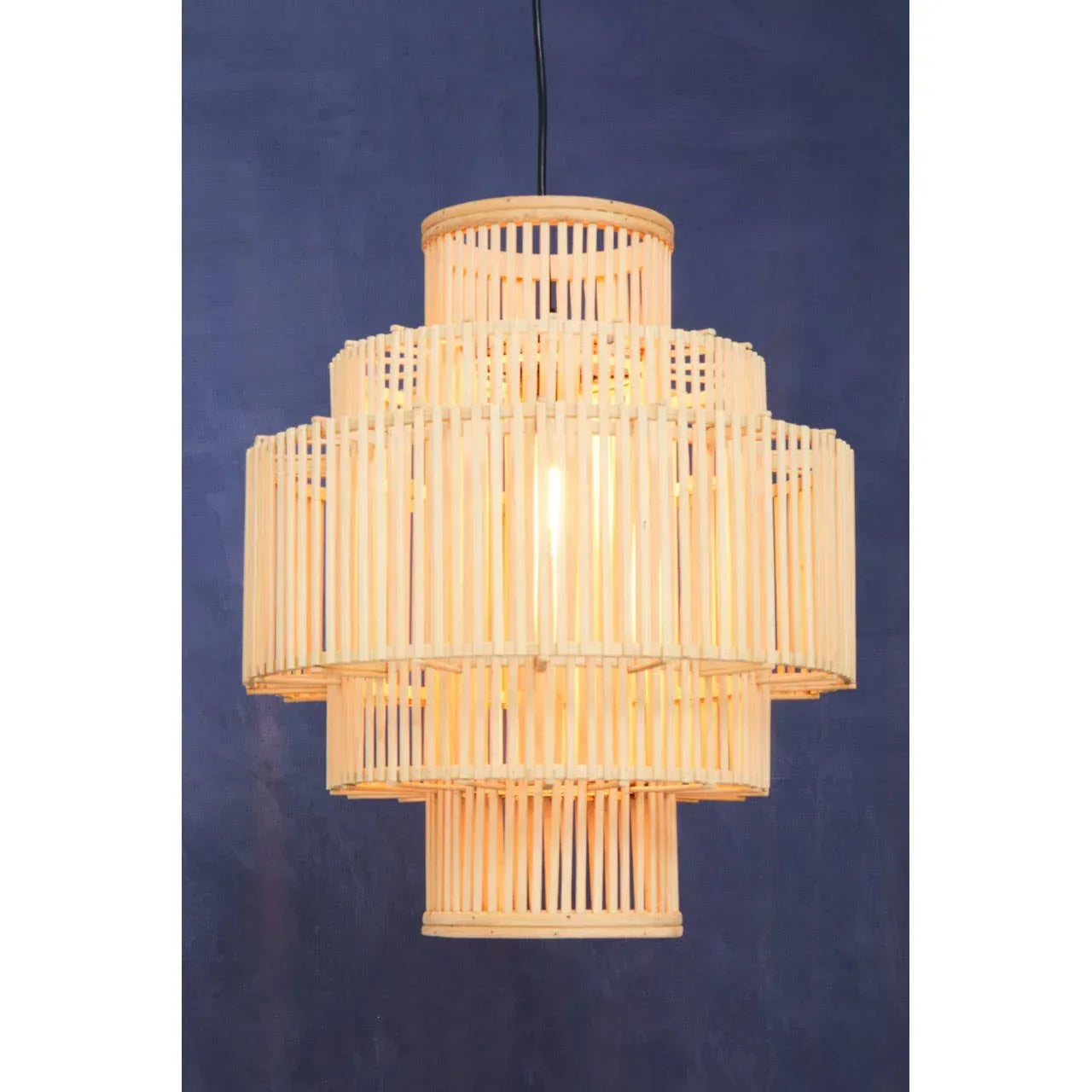 Natural rattan pendant light with layered cylindrical design against blue wall