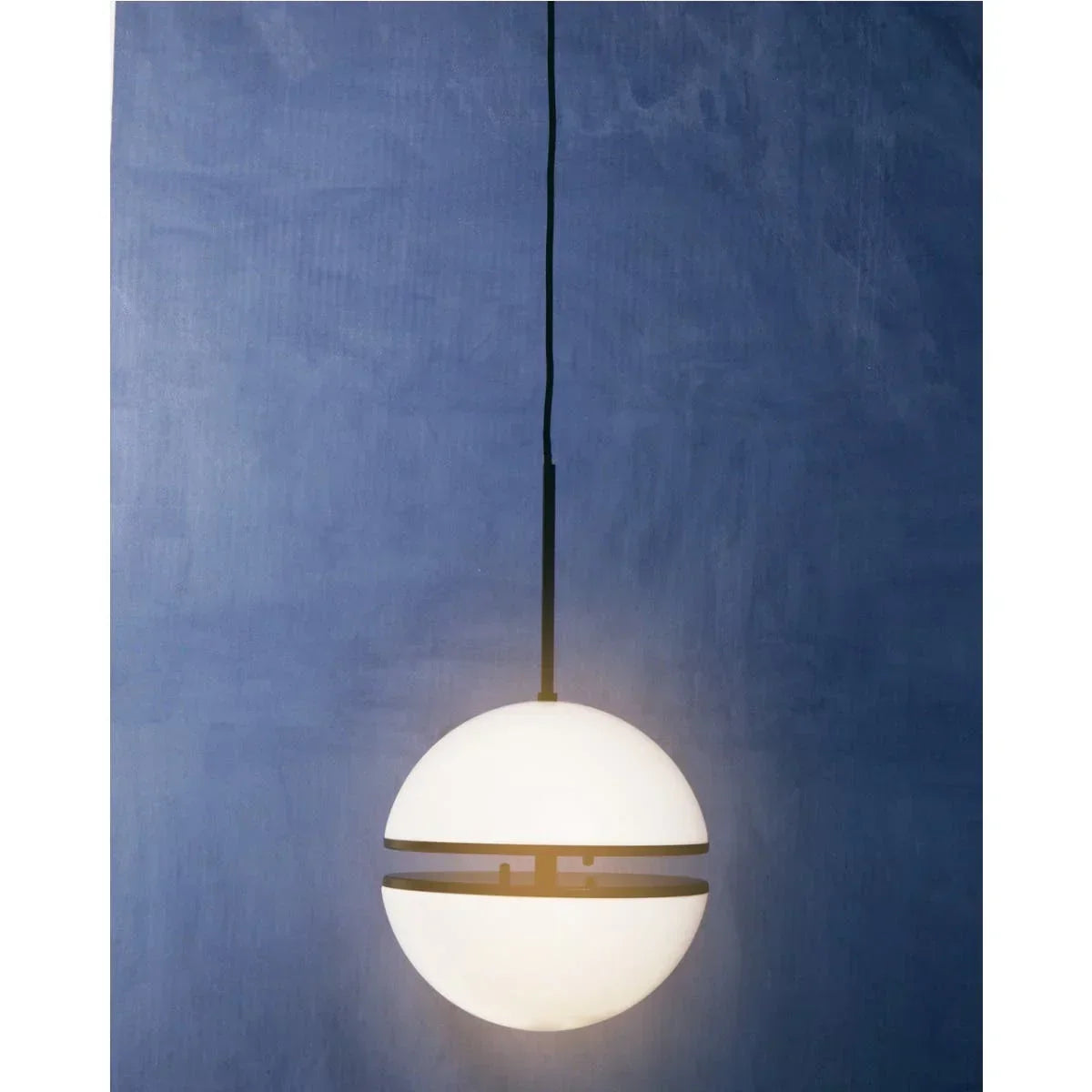 Globe pendant light with black trim hanging against a textured blue wall