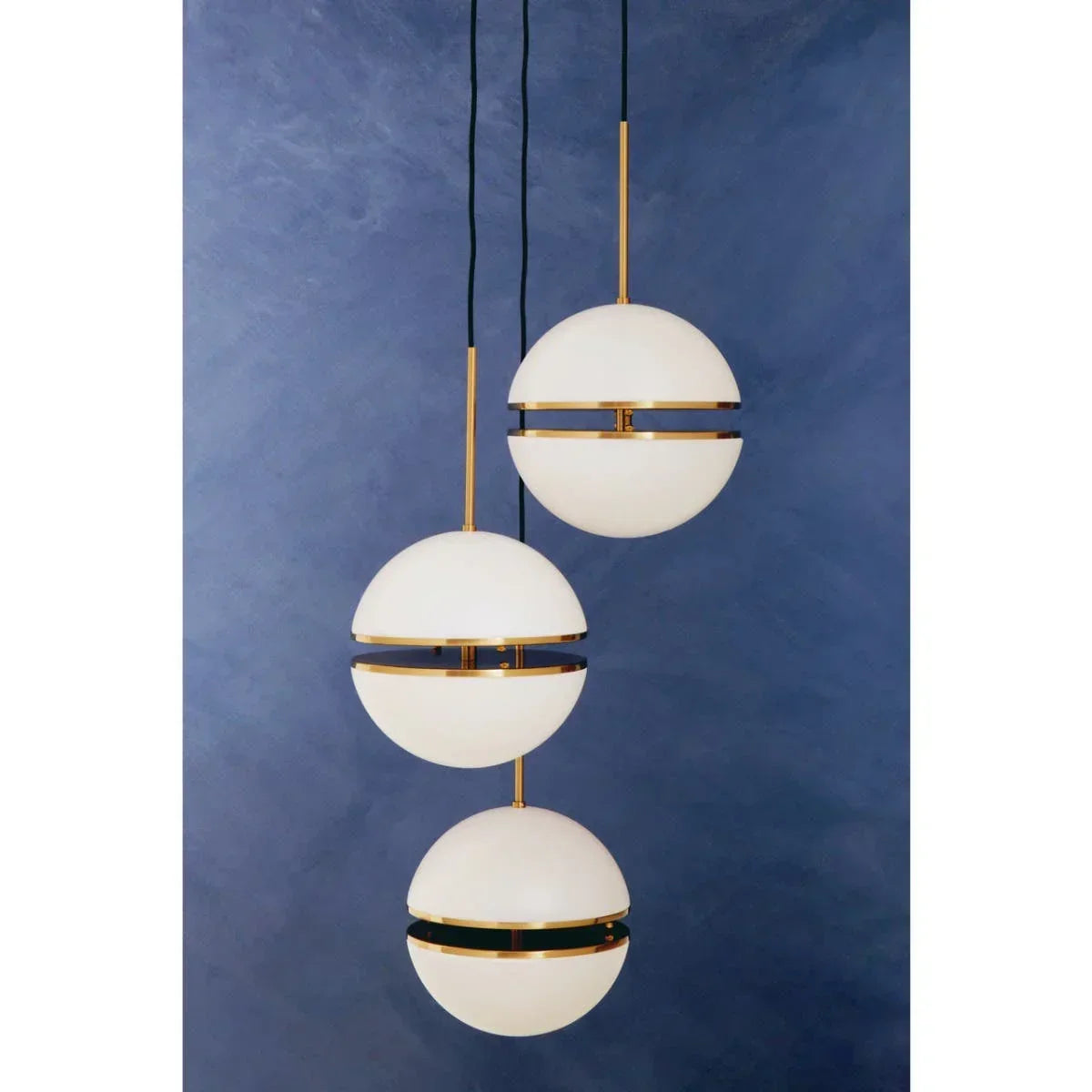 Three globe pendant lights with gold accents against a blue wall background