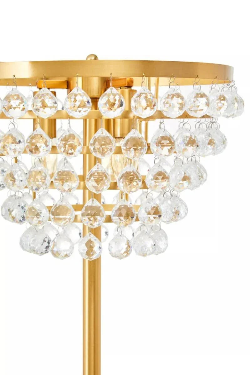 Gold table lamp with two-tiered clear crystal drops and metal base, close-up view