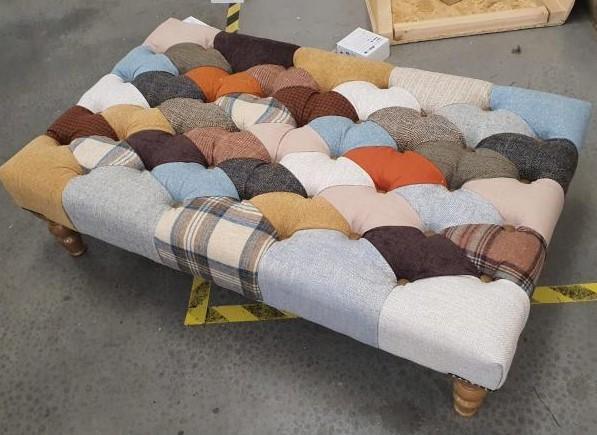 Patchwork fabric ottoman with tufted design and wooden legs in workshop setting