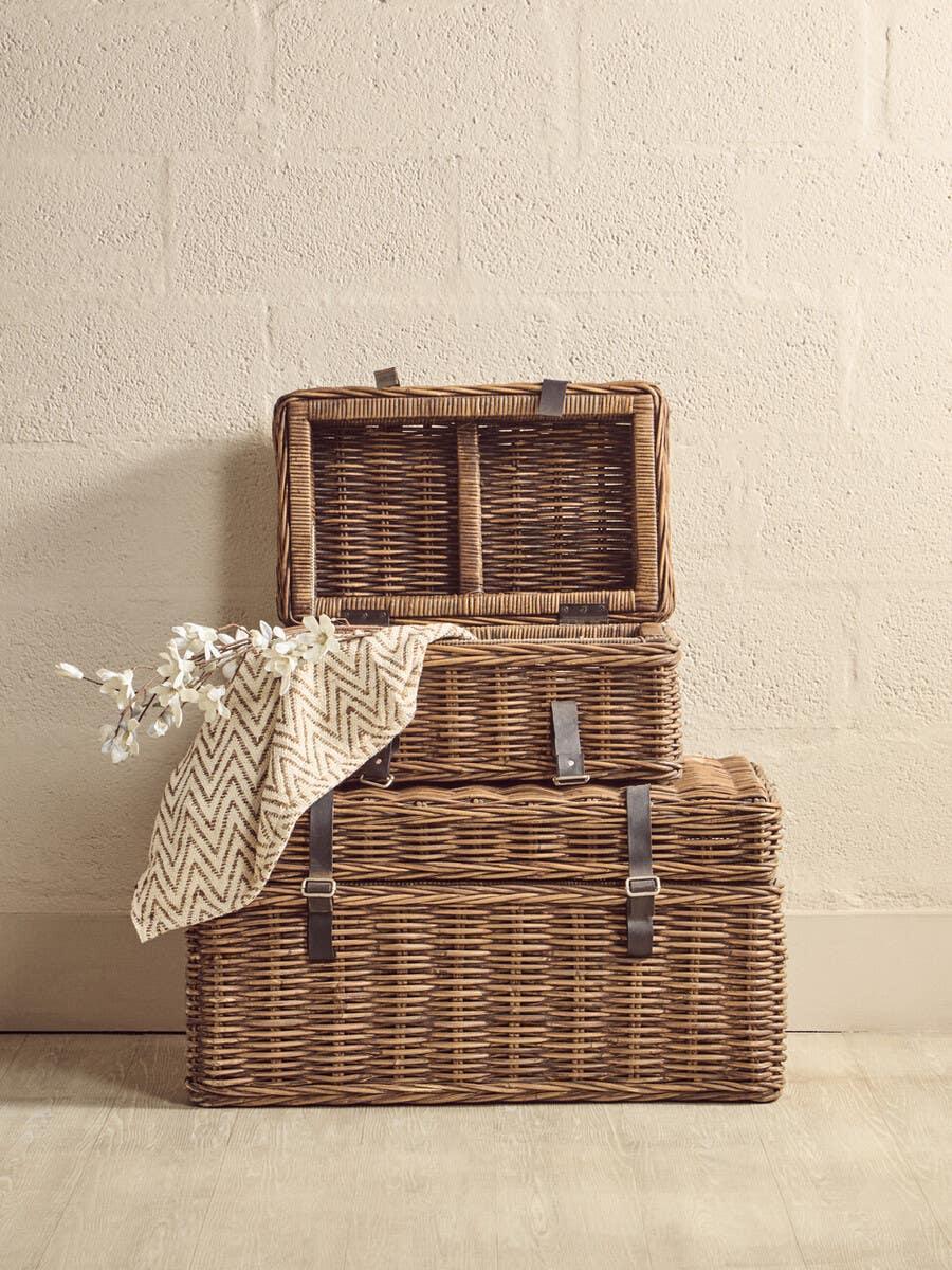 Set of three wicker storage baskets with leather straps, throw blanket and flowers