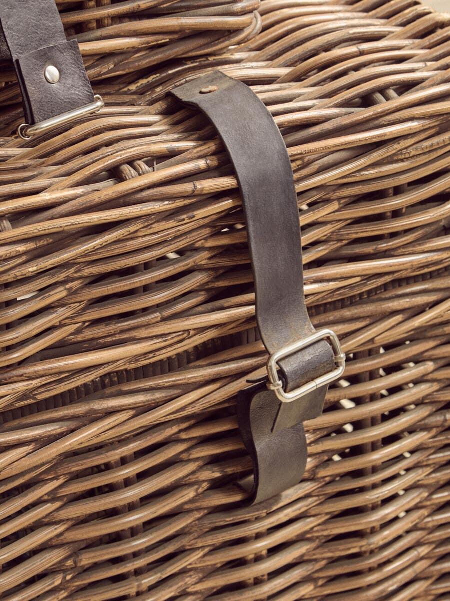 Wicker storage trunk with leather strap and metal buckle close-up
