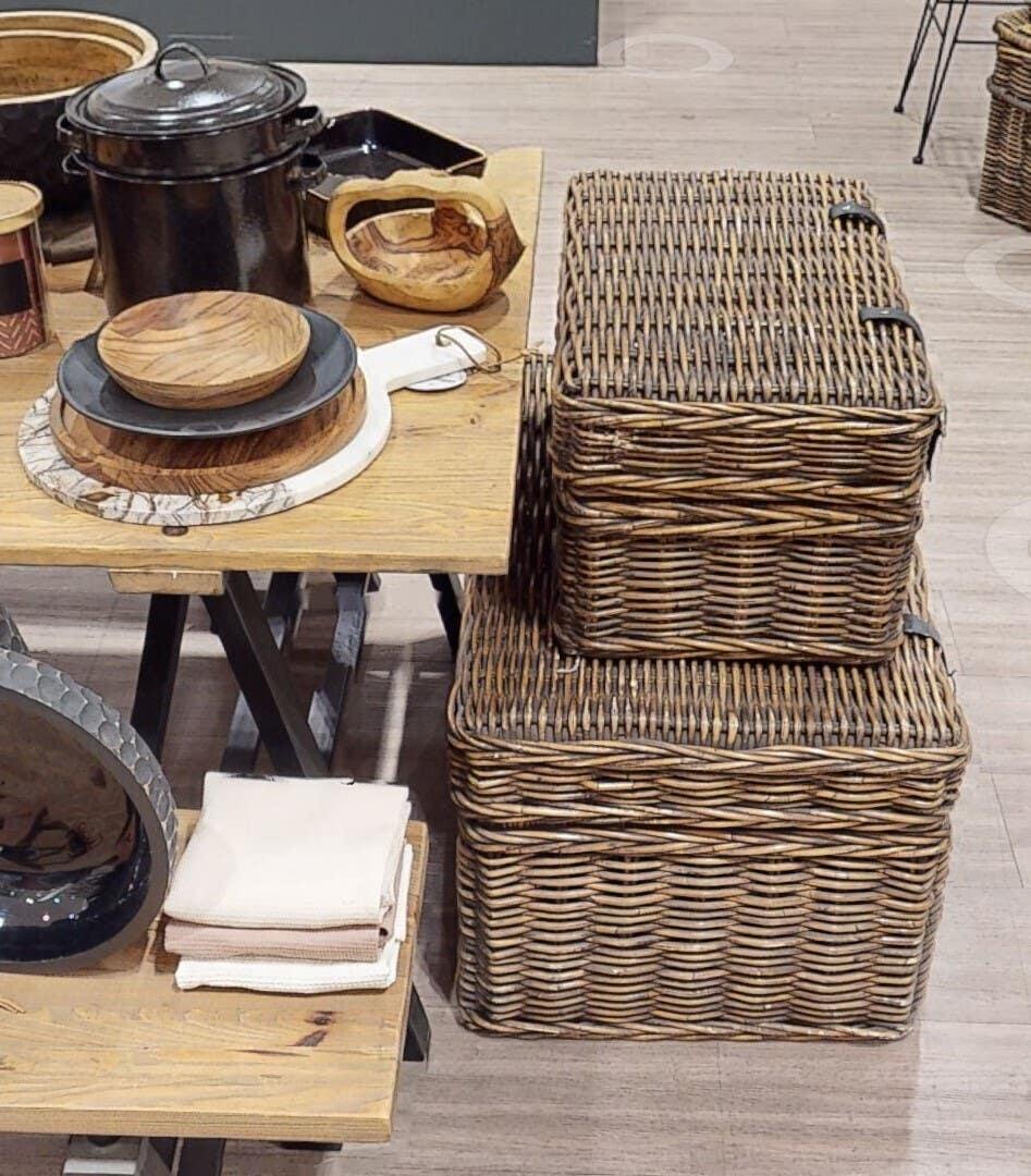 Wicker storage baskets stacked beside wooden dining table with kitchenware