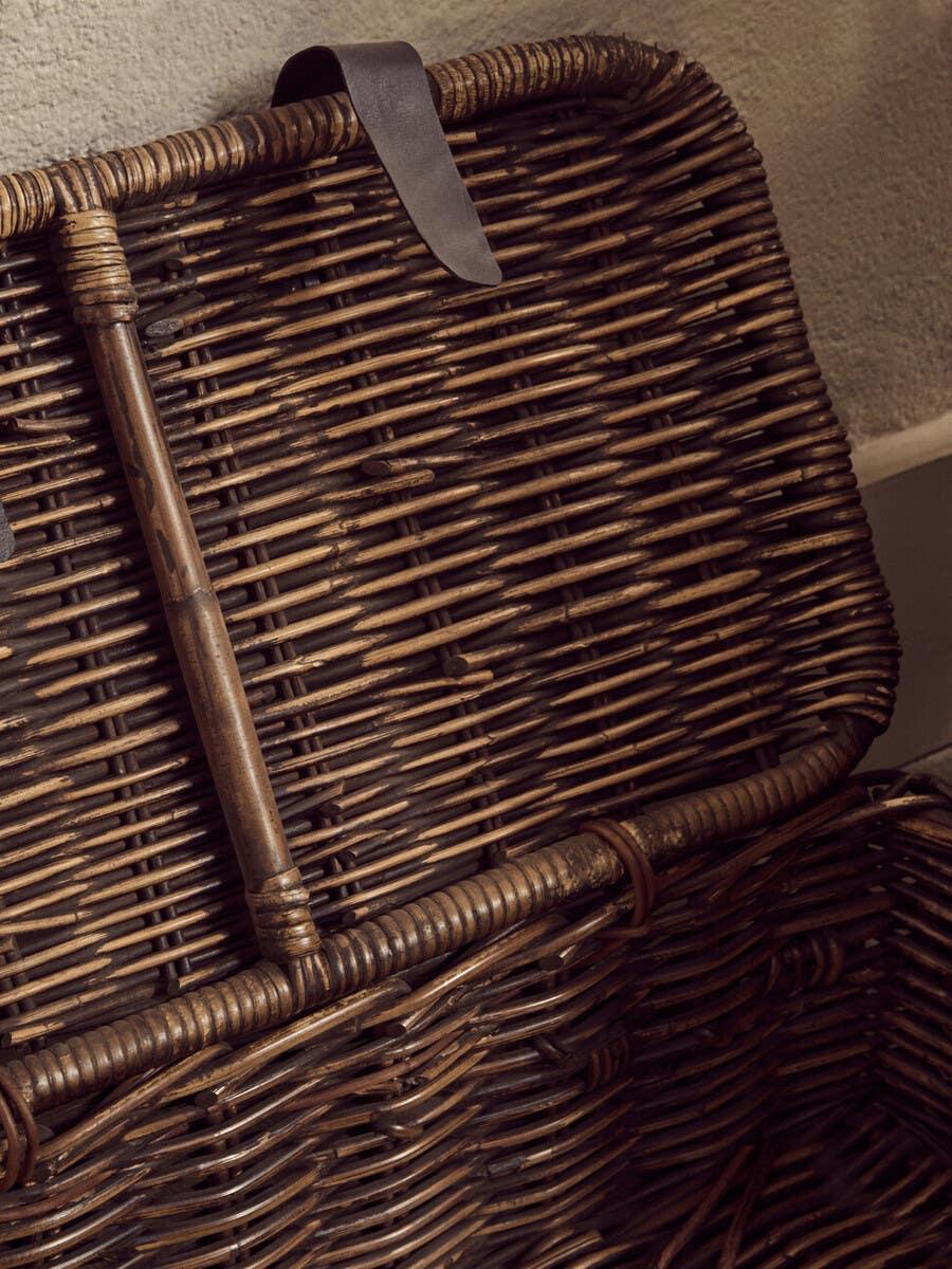 Closeup of open wicker storage basket with leather loop detail on lid