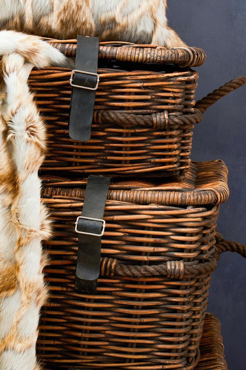 Stacked wicker storage baskets with rope handles and black leather buckle straps