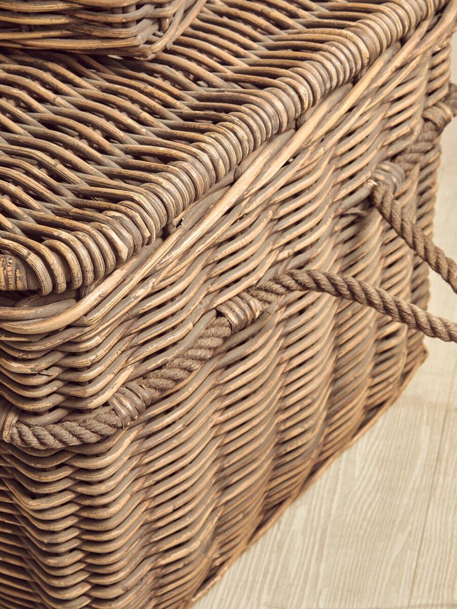 Wicker storage basket with rope handles on wooden floor, close up of woven texture